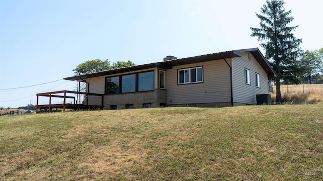 back of house with a chimney, central AC unit, a lawn, and a wooden deck