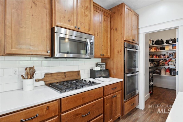 1041 White Horse Ridge Dr, Middleton, ID 83644 - kitchen featuring appliances with stainless steel finishes, backsplash, dark wood-style flooring, and light countertops