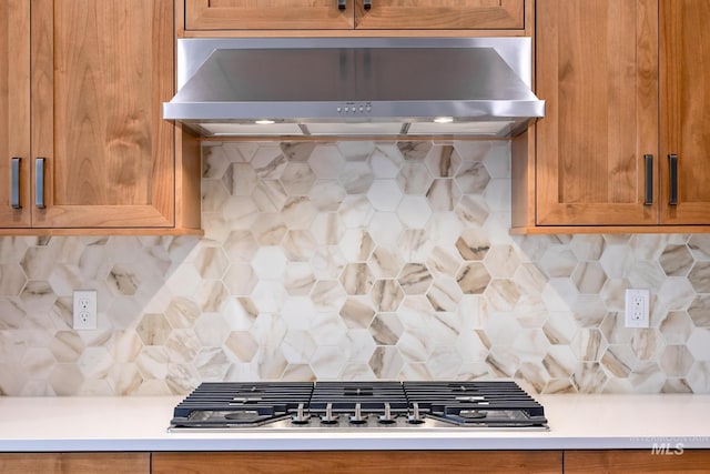 kitchen with wall chimney range hood, decorative backsplash, and stainless steel gas stovetop