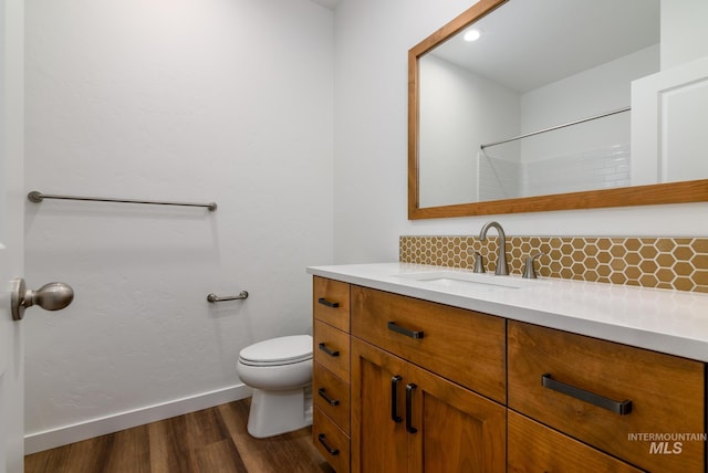 bathroom featuring hardwood / wood-style flooring, vanity, toilet, and backsplash