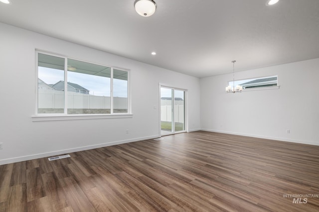 spare room with dark wood-type flooring, a wall unit AC, and a chandelier