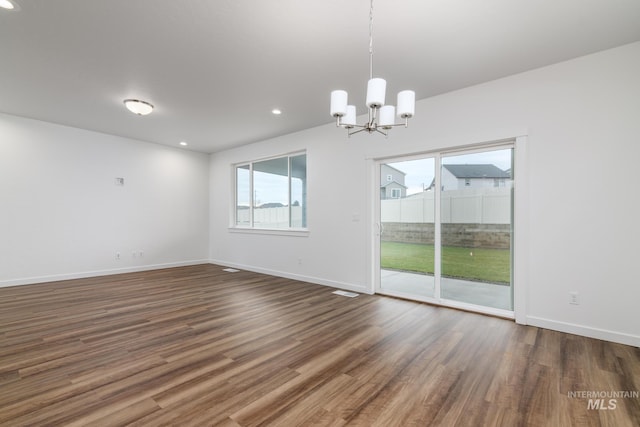 unfurnished room with dark wood-type flooring and a chandelier