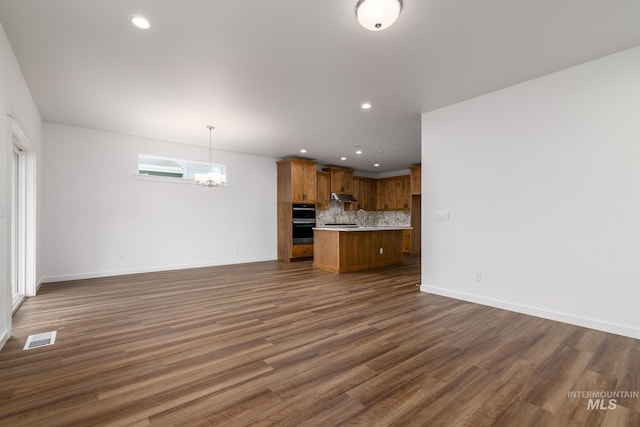 unfurnished living room featuring dark hardwood / wood-style flooring, a chandelier, and sink