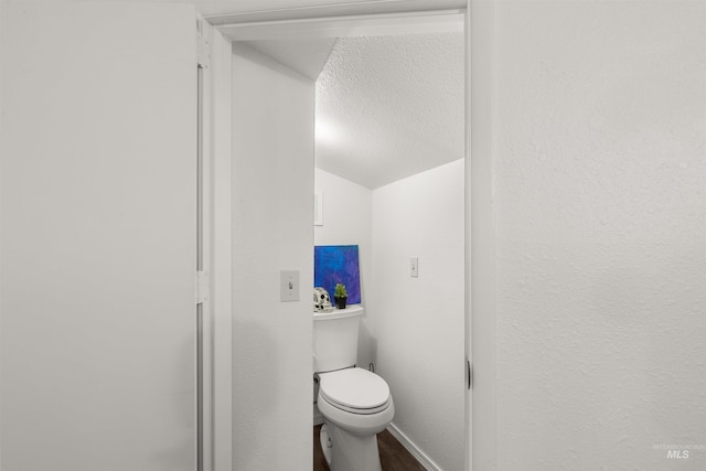 bathroom with a textured ceiling, toilet, and vaulted ceiling