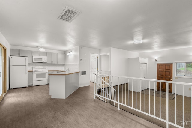 kitchen featuring kitchen peninsula, light hardwood / wood-style flooring, tasteful backsplash, and white appliances