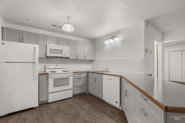 kitchen with tasteful backsplash, white appliances, sink, hardwood / wood-style floors, and kitchen peninsula