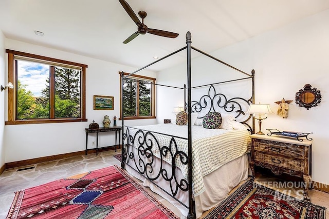 bedroom with stone tile floors, visible vents, ceiling fan, and baseboards