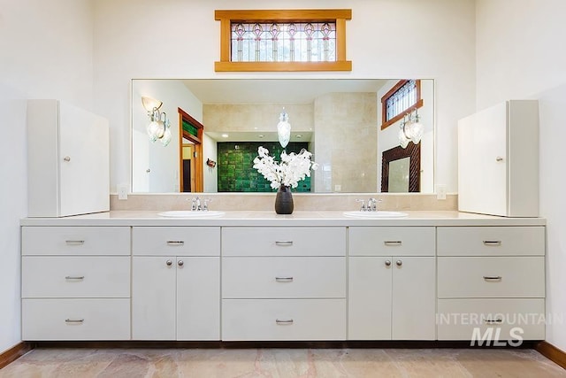 bathroom with double vanity, backsplash, baseboards, and a sink