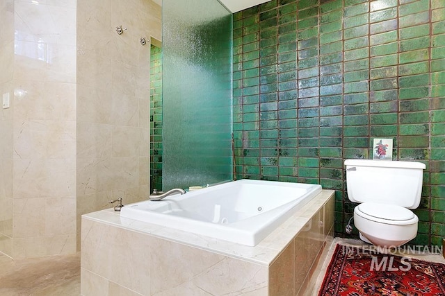 bathroom featuring tile patterned flooring, tile walls, a jetted tub, and toilet