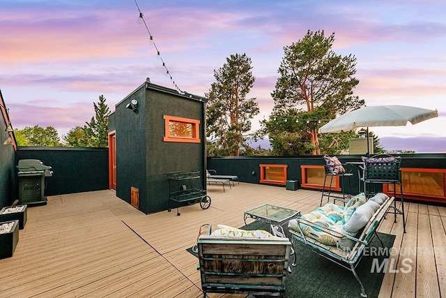 deck at dusk featuring grilling area