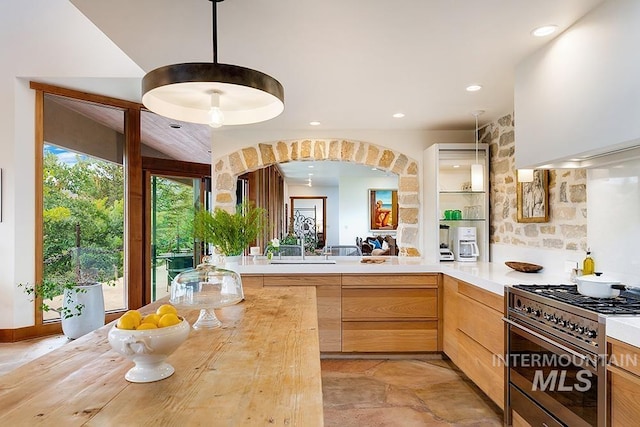 kitchen with high end stove, modern cabinets, pendant lighting, light brown cabinetry, and recessed lighting