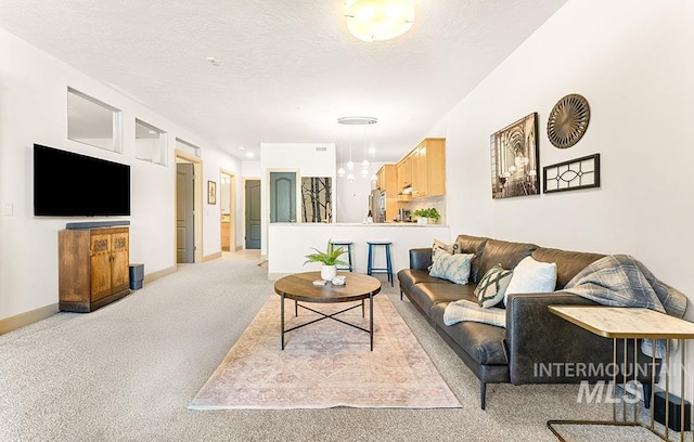 living area with a textured ceiling, light colored carpet, and baseboards