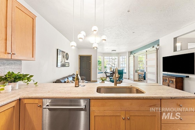 kitchen featuring a peninsula, dishwasher, a sink, open floor plan, and decorative light fixtures