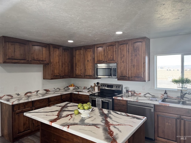 kitchen featuring a sink, light countertops, appliances with stainless steel finishes, a textured ceiling, and recessed lighting