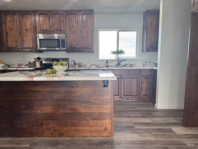 kitchen with dark wood-type flooring, visible vents, a sink, stainless steel appliances, and baseboards