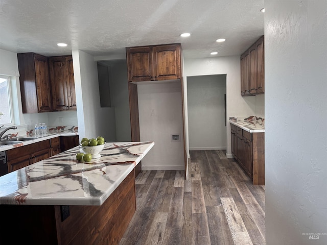 kitchen featuring a center island, a sink, dark wood-style flooring, light countertops, and a textured ceiling