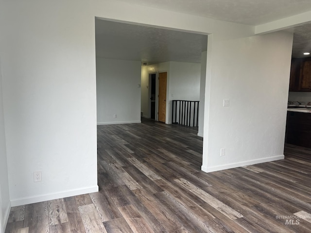 unfurnished room featuring baseboards and dark wood-style floors