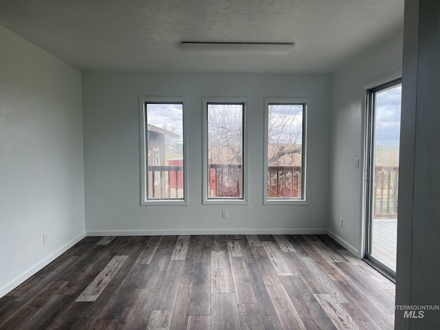 spare room featuring dark wood-type flooring and baseboards