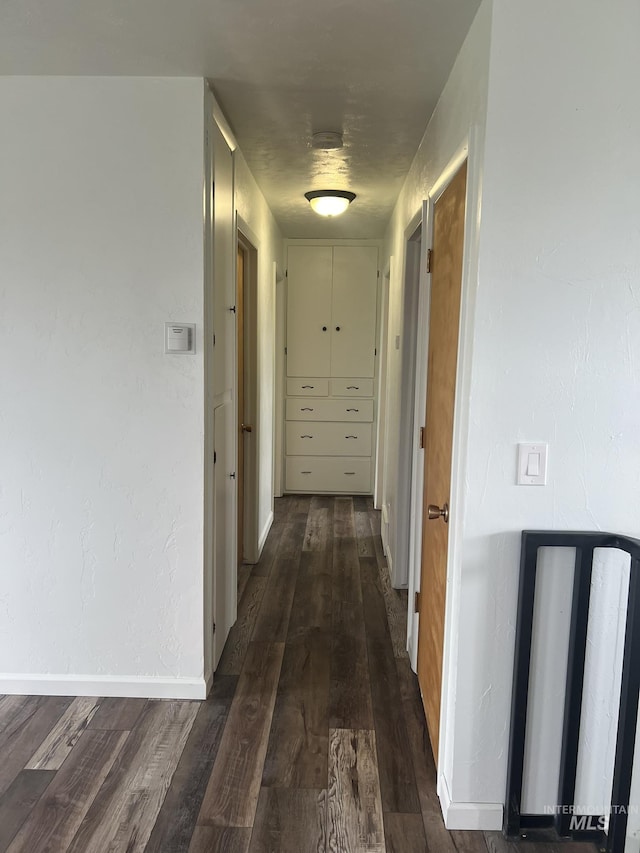 corridor featuring dark wood-style flooring and baseboards