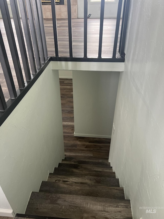stairs featuring wood finished floors and a textured wall