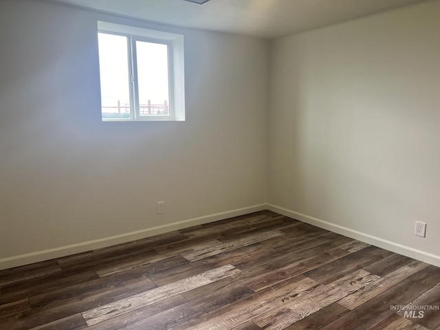 empty room featuring dark wood-style flooring and baseboards