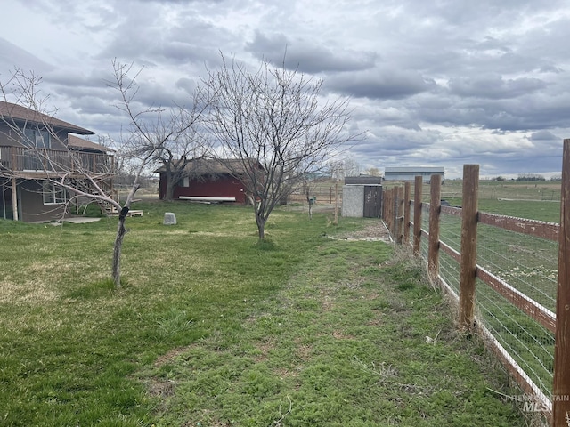 view of yard with a rural view, fence, and an outbuilding