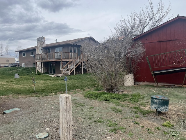 rear view of property featuring a barn, an outdoor structure, stairs, a yard, and a deck