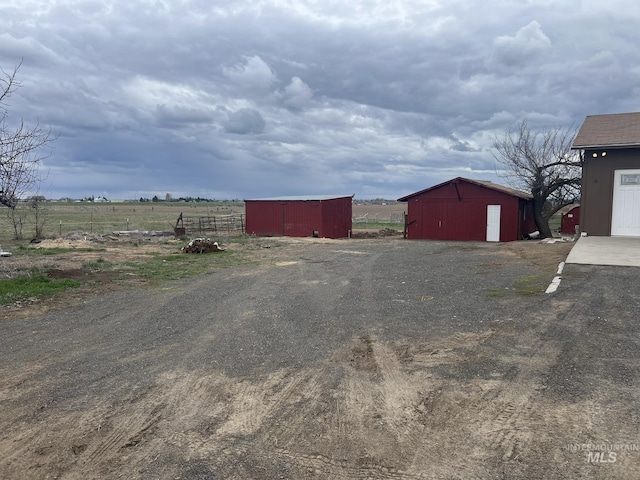 view of yard with a rural view, fence, and an outbuilding