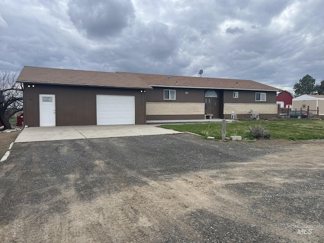 ranch-style home with a garage, driveway, and a shingled roof