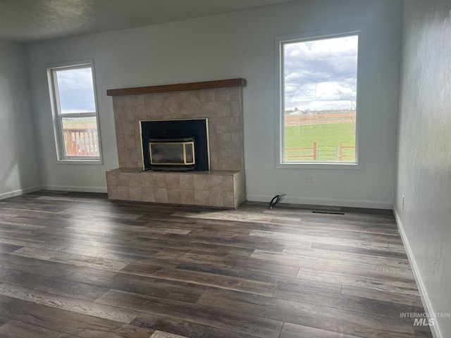 unfurnished living room with wood finished floors, a fireplace, and baseboards