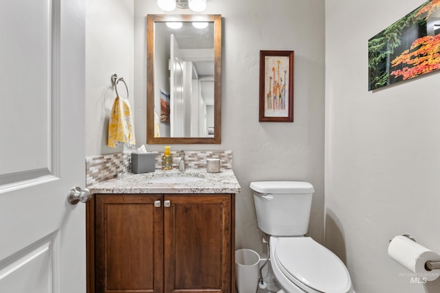 half bathroom featuring backsplash, vanity, and toilet