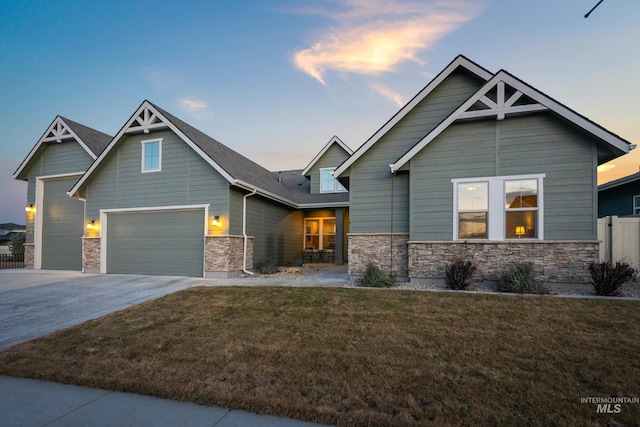 craftsman-style house featuring a front yard, fence, stone siding, and driveway