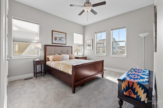 bedroom featuring a ceiling fan, visible vents, baseboards, and light carpet