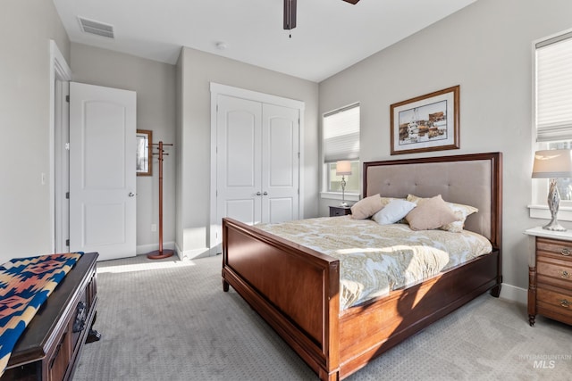 bedroom featuring baseboards, visible vents, light carpet, and a closet