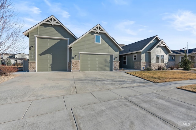 craftsman house with stone siding, an attached garage, an outbuilding, and driveway