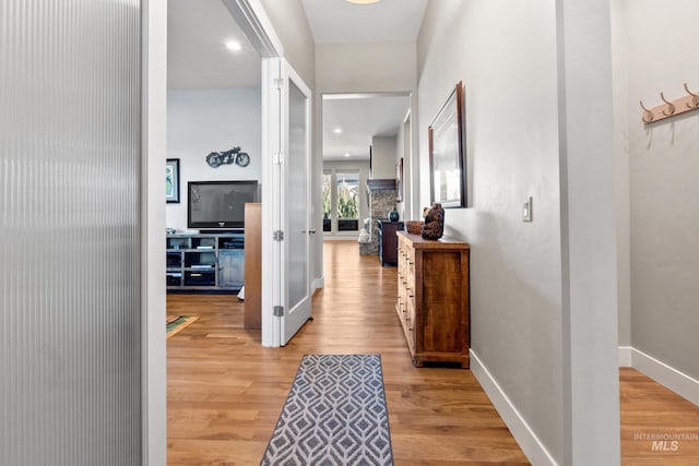 corridor featuring light wood-type flooring and baseboards