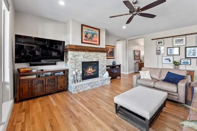 living room with a ceiling fan, baseboards, a fireplace, recessed lighting, and light wood-style floors