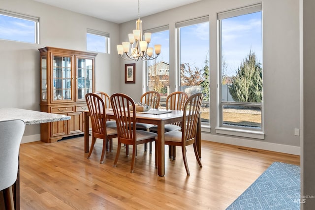 dining area featuring baseboards, light wood-type flooring, and a chandelier