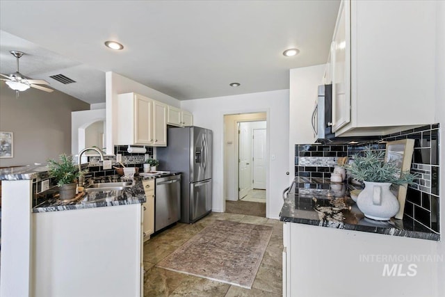 kitchen with visible vents, a sink, tasteful backsplash, stainless steel appliances, and ceiling fan