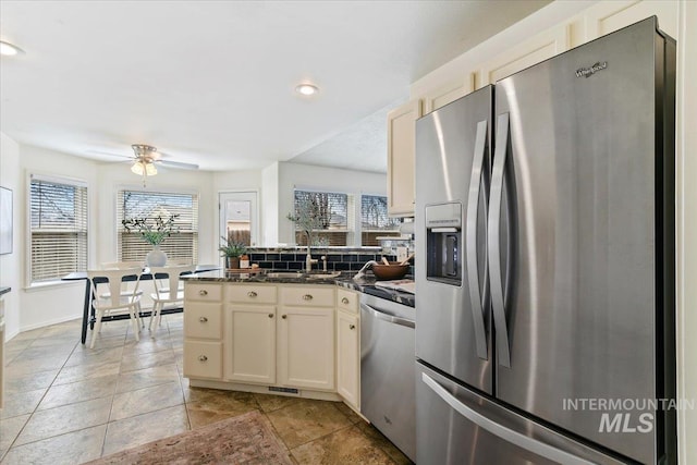 kitchen with a healthy amount of sunlight, a peninsula, stainless steel appliances, and a sink