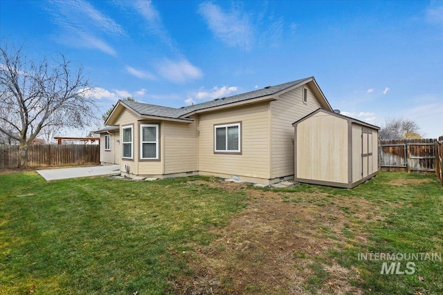 back of house with a yard, a fenced backyard, an outdoor structure, a storage unit, and a patio