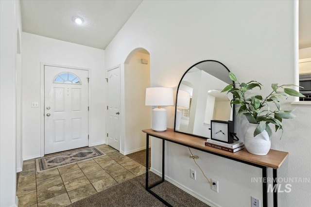 foyer entrance featuring baseboards and arched walkways