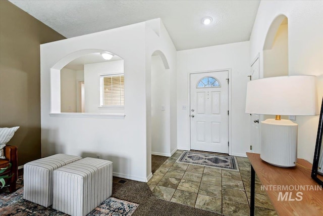 foyer entrance featuring baseboards and a textured ceiling