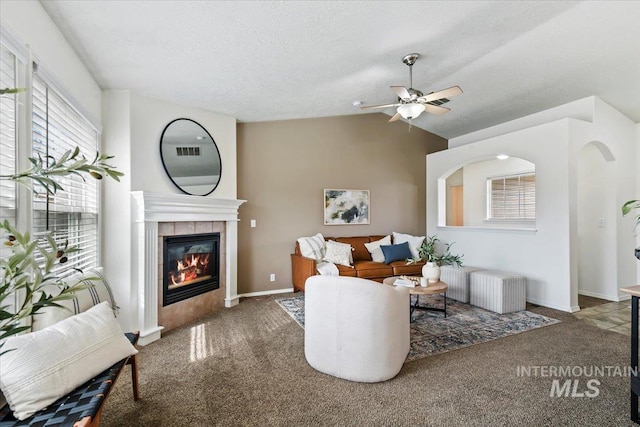 carpeted living room with a tiled fireplace, baseboards, a ceiling fan, and vaulted ceiling