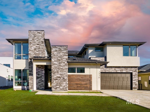 modern home with driveway, stone siding, a front lawn, and stucco siding