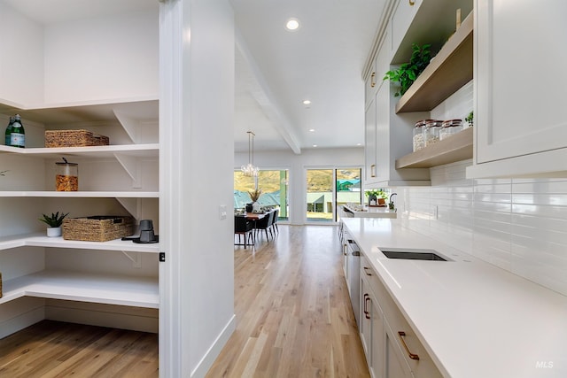 kitchen featuring open shelves, light wood finished floors, light countertops, and tasteful backsplash