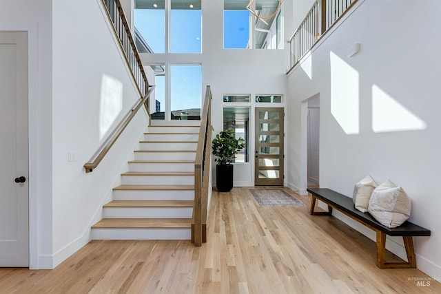 entrance foyer with a high ceiling, stairway, wood finished floors, and a healthy amount of sunlight