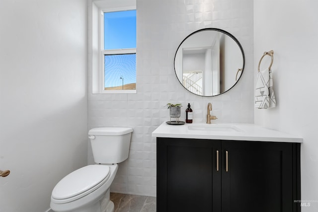 half bath with tile walls, vanity, and toilet