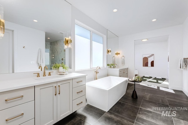 bathroom with recessed lighting, two vanities, a sink, and a shower stall