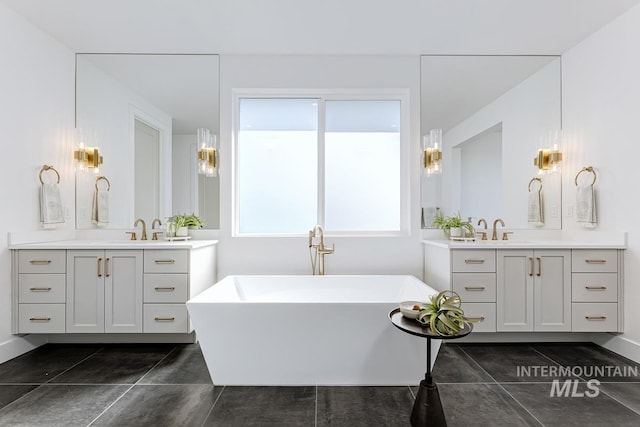 full bathroom featuring a freestanding tub, two vanities, and tile patterned floors